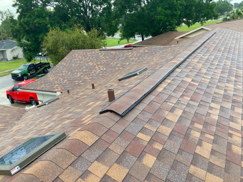 new shingle roof with skylights, and a view of a Westfall Roofing truck on the street below