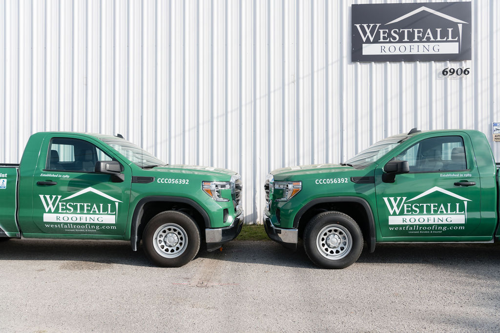 two Westfall Roofing trucks in front of fully licensed & insured Westfall Roofing's building