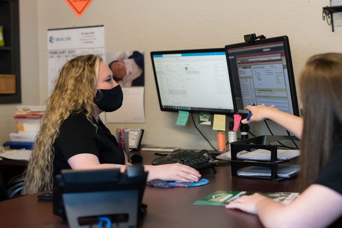 Team members in the Westfall Roofing office working at a computer.