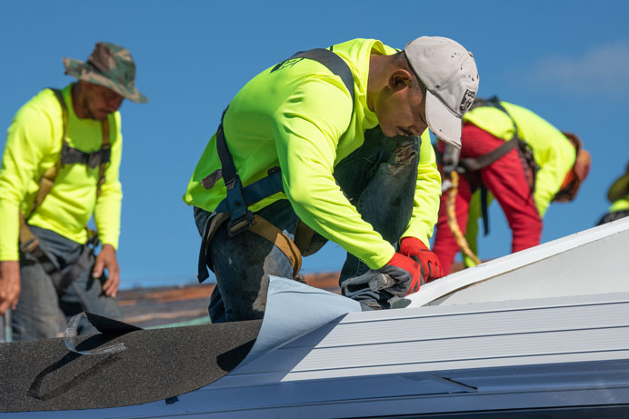 team of roofers installing underlayment on a roof