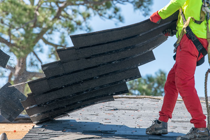 roofer tearing off an old roof before roof replacement