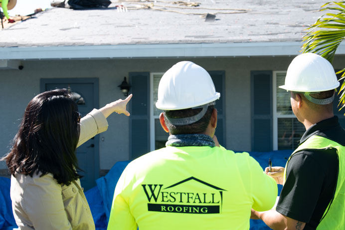 Westfall Roofing team members consulting with a homeowner