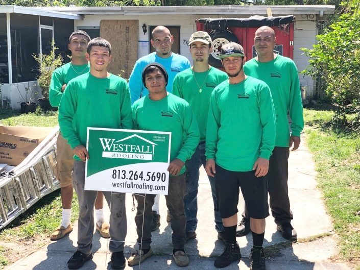 Westfall Roofing crew in front of a house, holding a Westfall Roofing sign