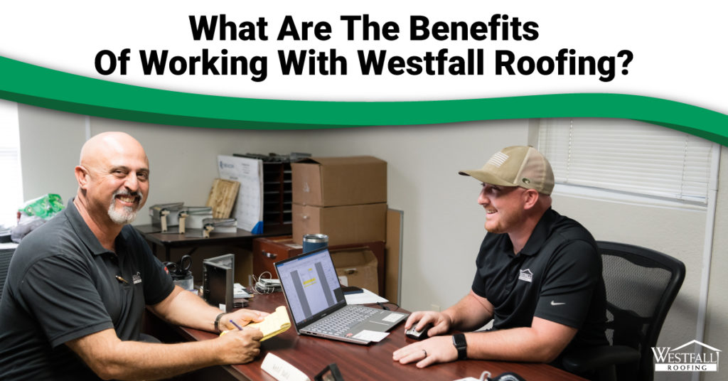 Two men meeting at a desk with the caption "What Are The Benefits Of Working With Westfall Roofing?"