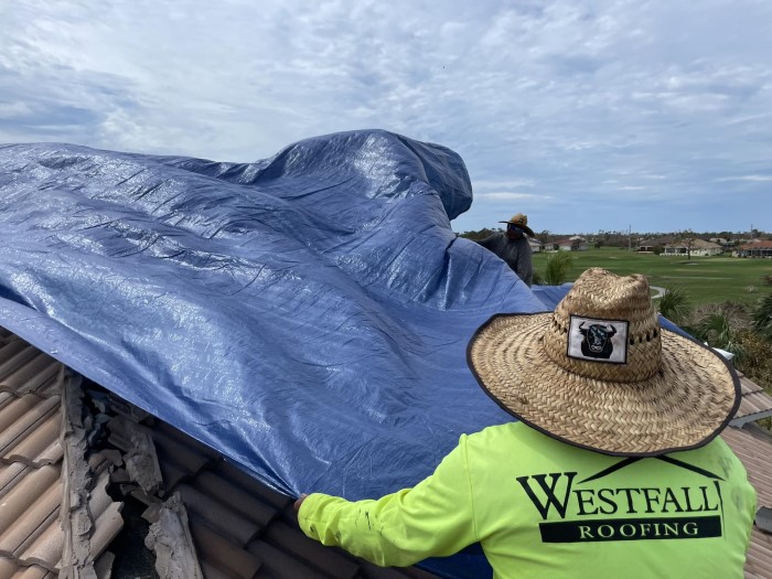 Westfall Roofing roofing contractor applying tarp to a damaged tile roof in Tampa